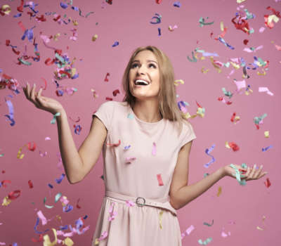 Studio shot of successful young woman celebrating achievement with confetti